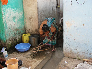 A woman at Shakti Nagar slum drinking water from a polluted source